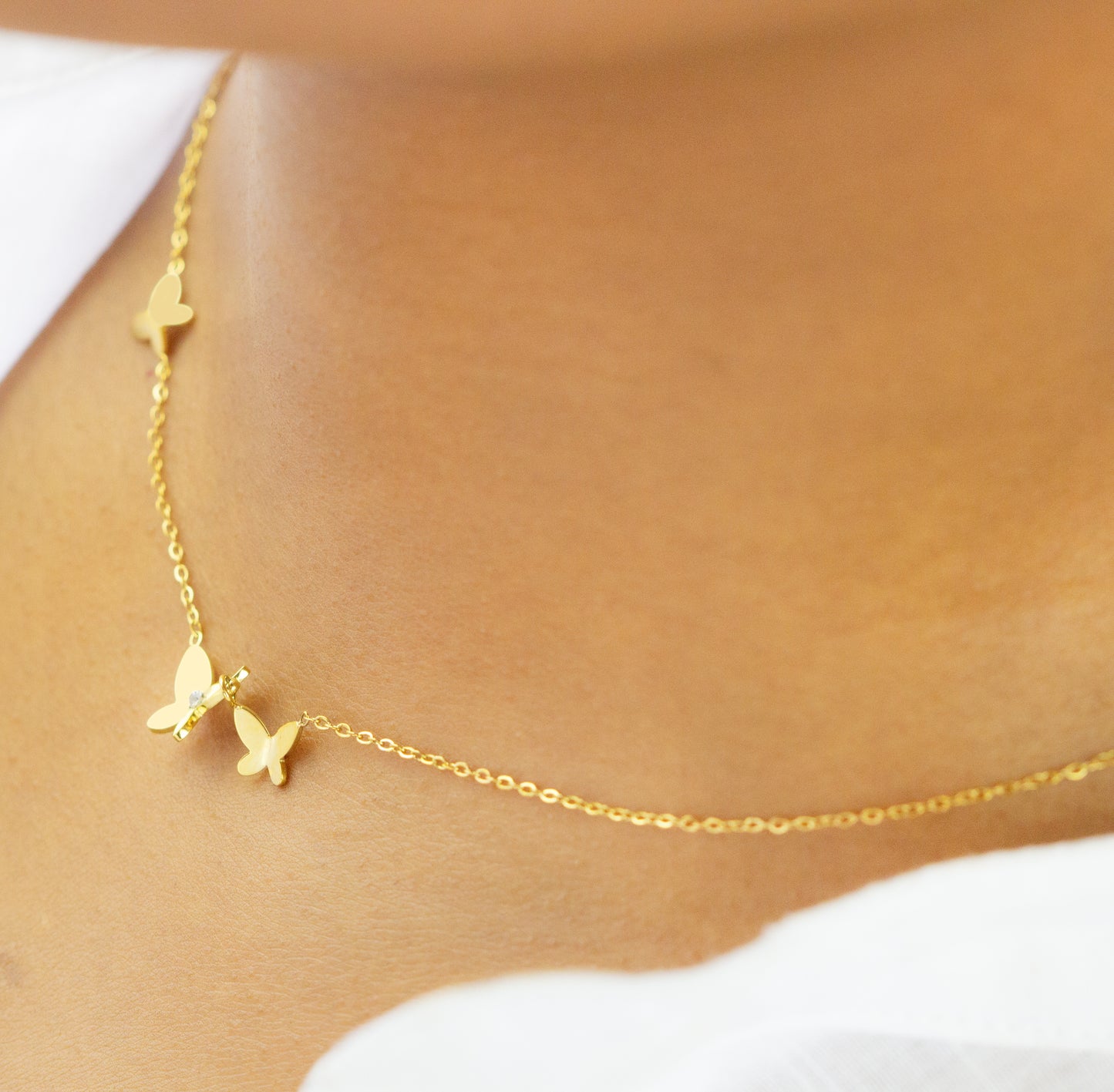 A model wearing a delicate gold necklace featuring small butterfly charms from Dahlia Jewels. The elegant design highlights the beauty of simplicity. Dahlia Jewels offers free delivery in Nairobi.