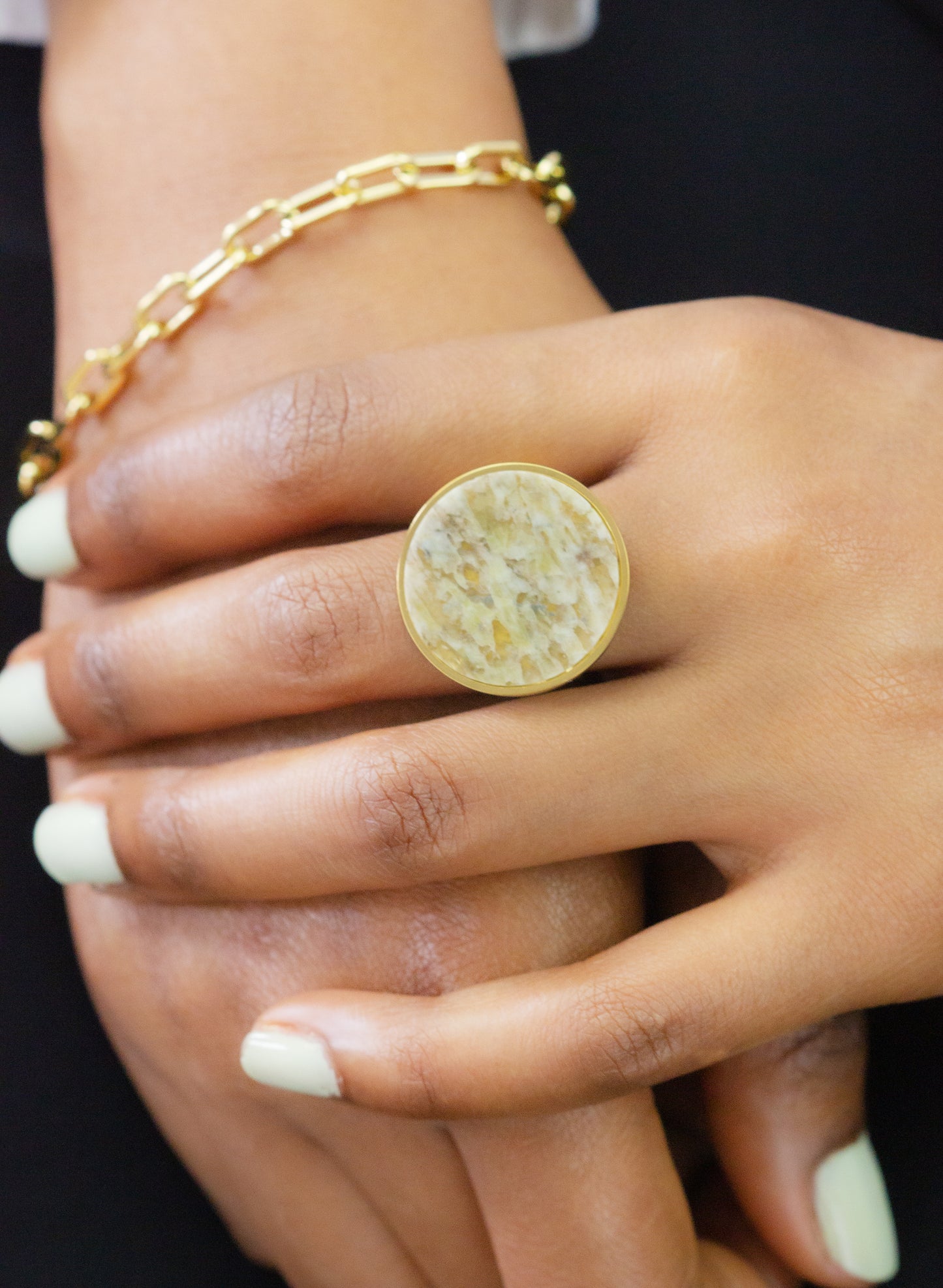 Close-up of a model's hand showcasing a unique stone ring and a delicate gold bracelet from Dahlia Jewels. Enjoy free delivery in Nairobi on all orders. Enhance your collection with this stylish jewellery piece.