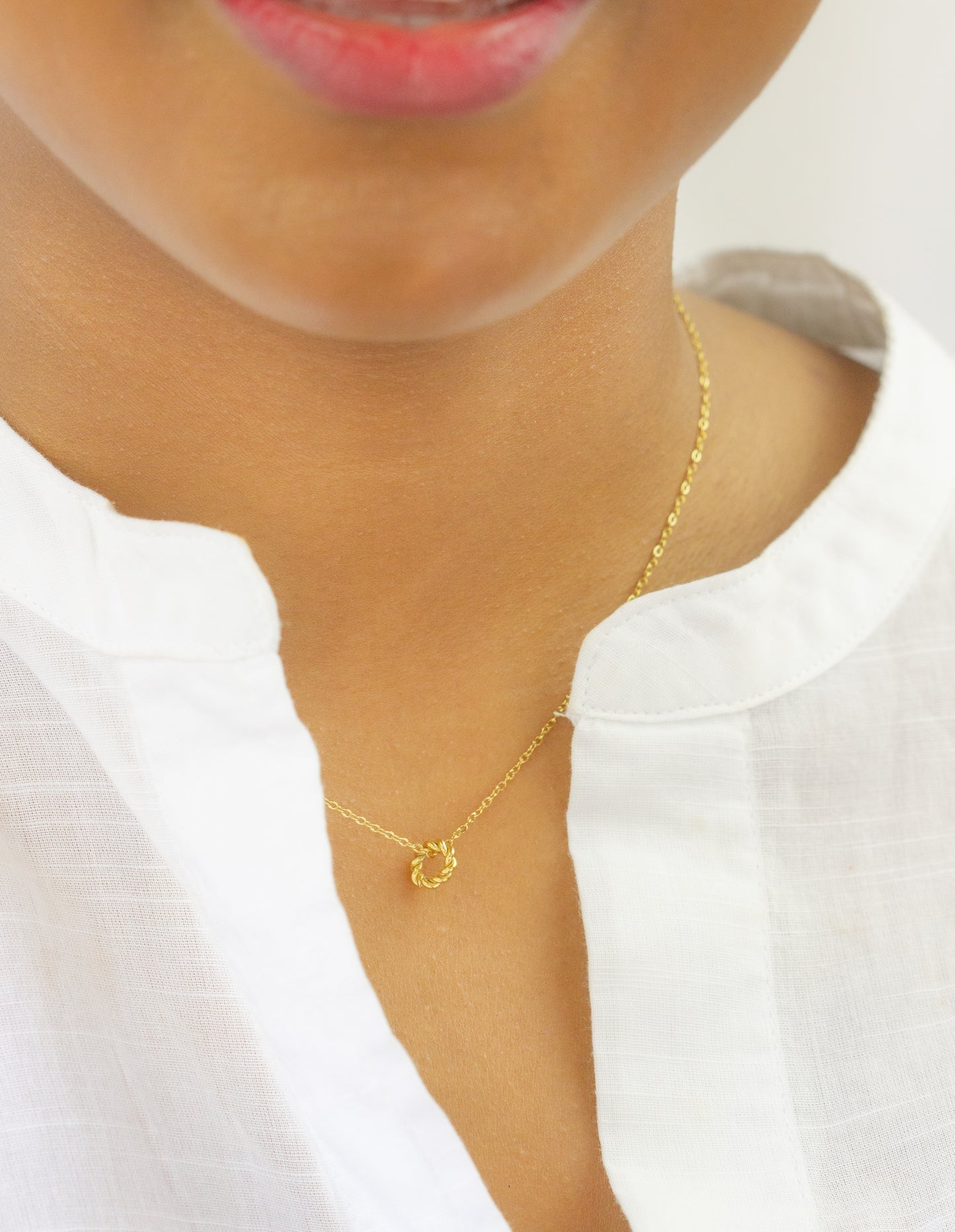 Close-up of a model wearing a gold-plated necklace with a twisted circle pendant from Dahlia Jewels. This delicate jewelry piece adds a subtle elegance to any outfit. Enjoy free delivery in Nairobi.