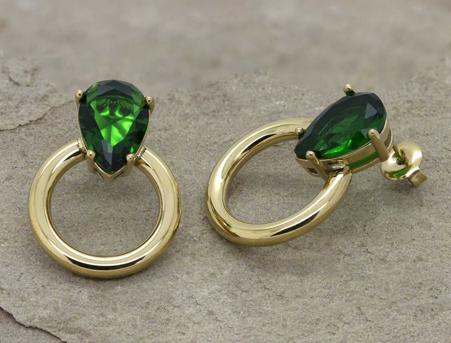 Dahlia Jewels presents exquisite gold-tone hoop earrings, each featuring a prominent green gemstone, marrying timeless elegance with a dash of vivid color. Enjoy complimentary jewelry delivery in Nairobi.