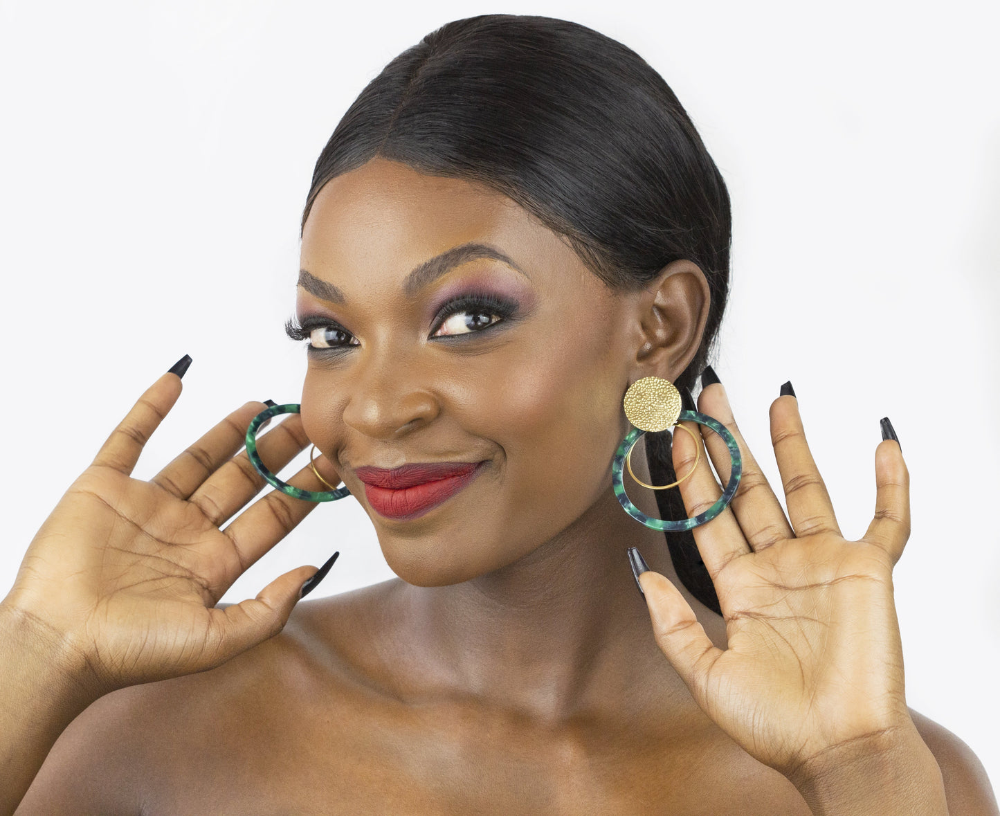 Model showcasing a vibrant pair of gold-plated earrings featuring a teardrop-shaped turquoise stone, and a gold chain bracelet with a delicate design. The jewelry enhances the model's look and reflects Dahlia Jewels' diverse collection, emphasizing free delivery in Nairobi. Keywords: jewelry, jewellery.