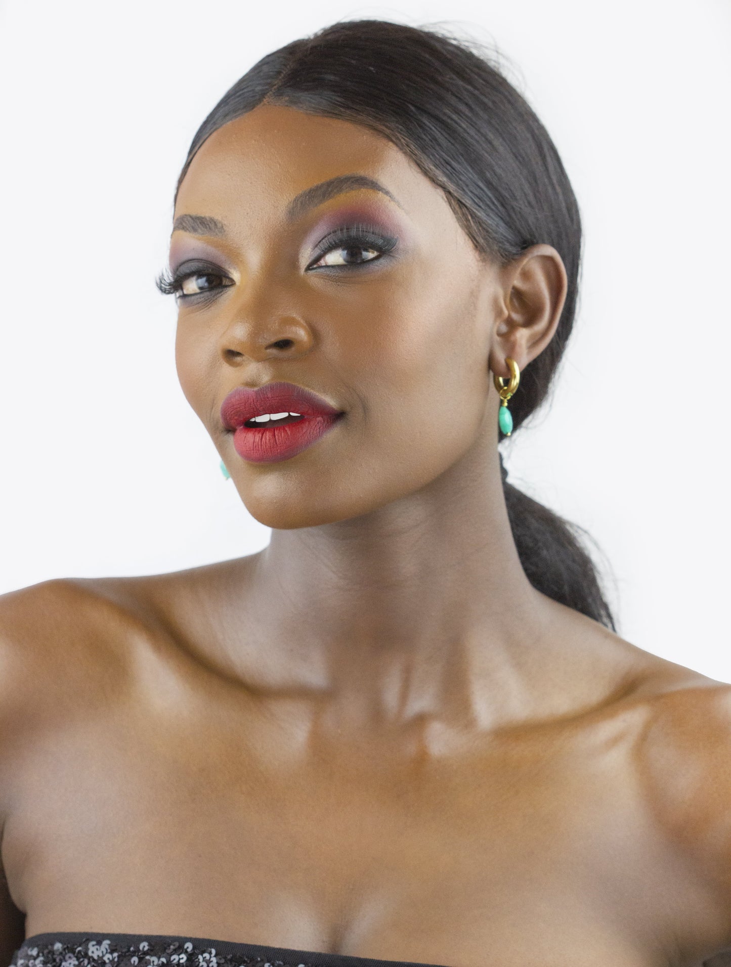 A model wears a bold, statement pair of earrings from Dahlia Jewels. One earring is circular with a textured gold disk on top, and below it, a double hoop design with a large green tortoiseshell ring and a smaller gold-plated ring. This vibrant piece of jewelry adds a touch of elegance and is perfect for special occasions. Dahlia Jewels provides free delivery in Nairobi, making it easier for locals to access luxurious jewelry. Keywords: jewelry, jewellery.