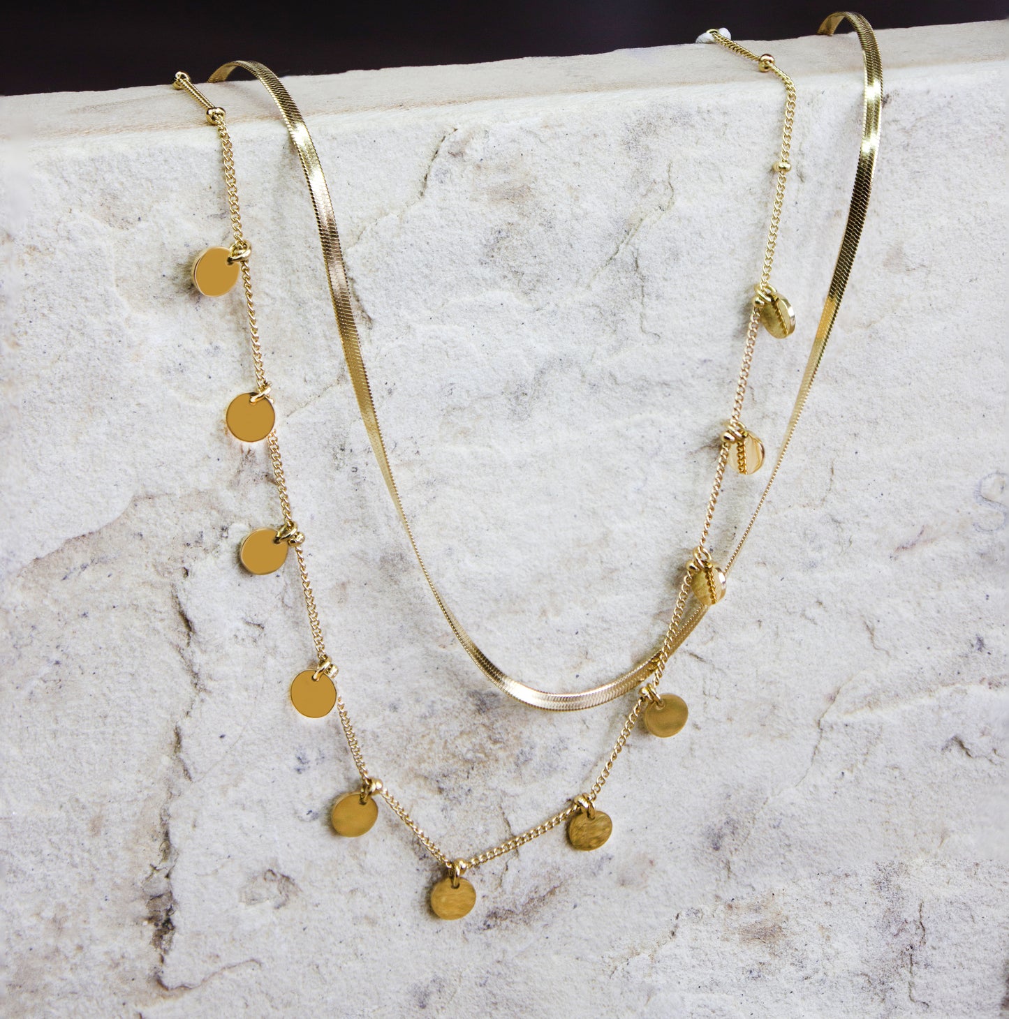 Sophisticated multi-strand gold-plated necklace from Dahlia Jewels, featuring an array of beautifully layered chains including a smooth snake chain and a finer chain adorned with small, polished disc charms. The mix of textures and styles offers a modern yet timeless appeal, perfect for accessorizing both casual and formal outfits. This necklace secures with a robust clasp and is designed to lay gracefully around the neck. Available for free delivery in Nairobi. Keywords: jewellery, jewelry.
