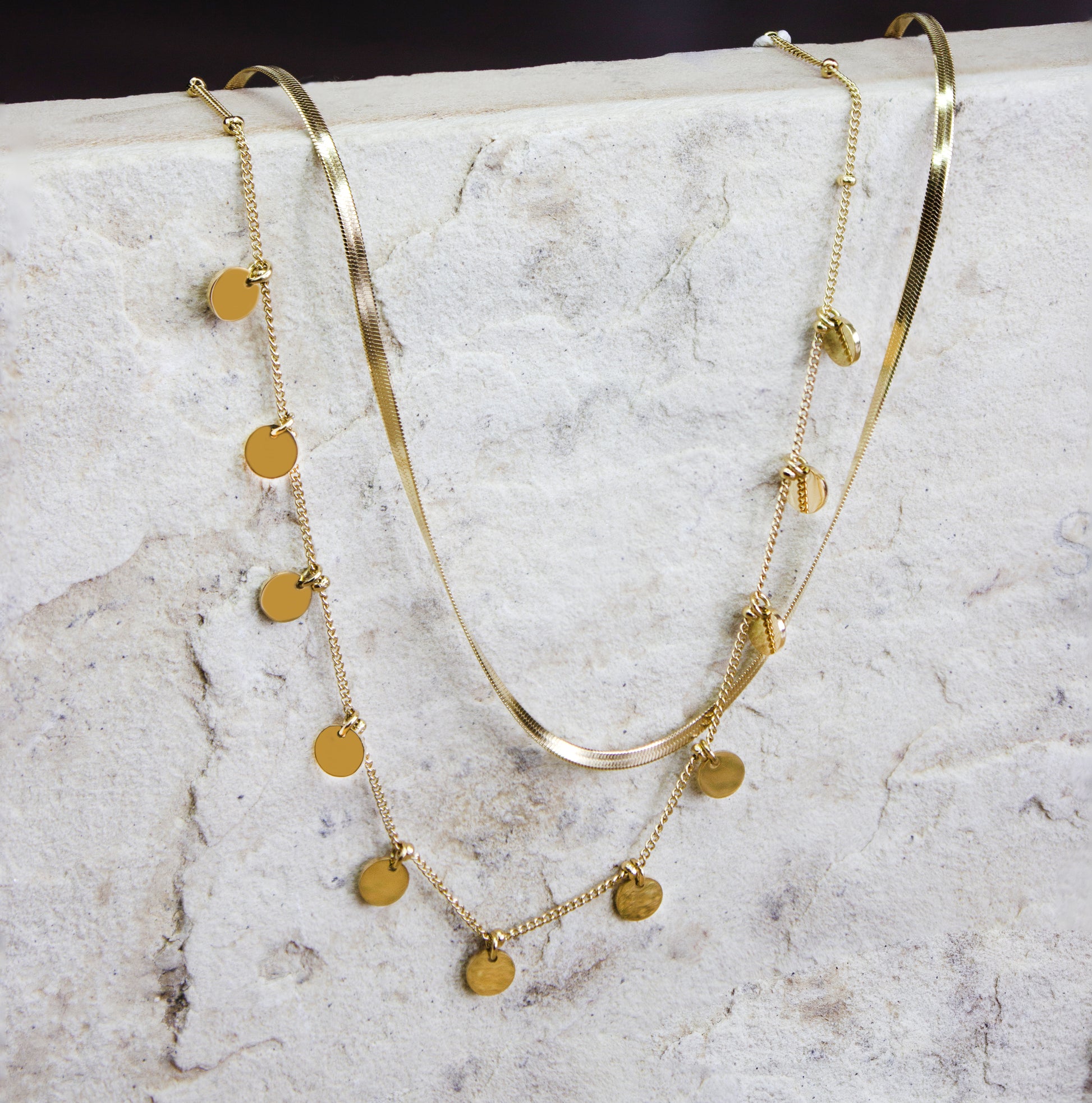 Sophisticated multi-strand gold-plated necklace from Dahlia Jewels, featuring an array of beautifully layered chains including a smooth snake chain and a finer chain adorned with small, polished disc charms. The mix of textures and styles offers a modern yet timeless appeal, perfect for accessorizing both casual and formal outfits. This necklace secures with a robust clasp and is designed to lay gracefully around the neck. Available for free delivery in Nairobi. Keywords: jewellery, jewelry.