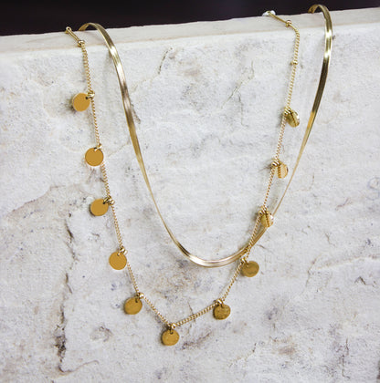 Sophisticated multi-strand gold-plated necklace from Dahlia Jewels, featuring an array of beautifully layered chains including a smooth snake chain and a finer chain adorned with small, polished disc charms. The mix of textures and styles offers a modern yet timeless appeal, perfect for accessorizing both casual and formal outfits. This necklace secures with a robust clasp and is designed to lay gracefully around the neck. Available for free delivery in Nairobi. Keywords: jewellery, jewelry.