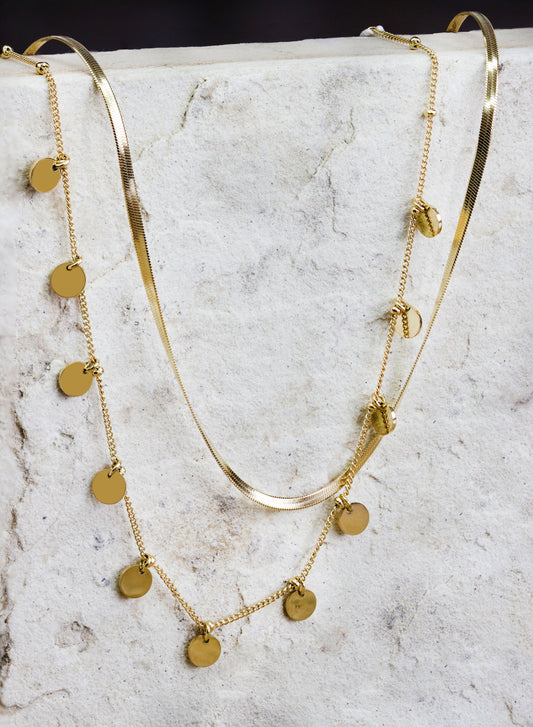 Chic multi-layered gold-plated necklace from Dahlia Jewels, featuring a combination of sleek snake chains and a delicate chain adorned with round disc charms. The varying textures and lengths add depth and sophistication, making this necklace a versatile accessory for enhancing any wardrobe. Ideal for both day-to-day elegance and special occasions, this piece secures with a classic clasp. Available for free delivery in Nairobi. Keywords: jewellery, jewelry.