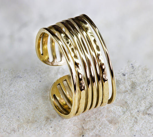 Elegant and modern gold-plated open band ring from Dahlia Jewels, featuring a series of parallel bars that create an airy, dynamic look. The design allows for a flexible fit, making it a versatile accessory for everyday wear or special occasions. The polished finish catches the light beautifully, emphasizing its high-quality craftsmanship. Available for free delivery in Nairobi. Keywords: jewellery, jewelry.