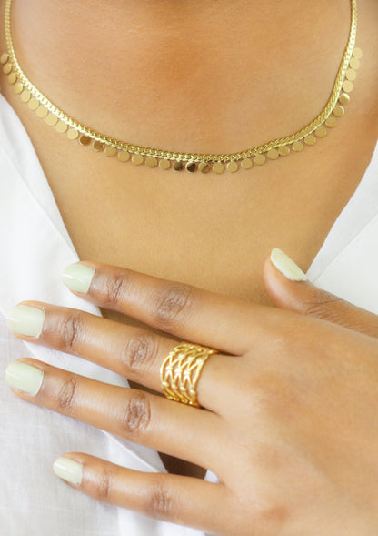 Close-up of a model showcasing a gold necklace with disc details and a matching intricate gold ring from Dahlia Jewels. Enjoy free delivery in Nairobi on all orders. Elevate your jewellery collection with these stunning pieces.