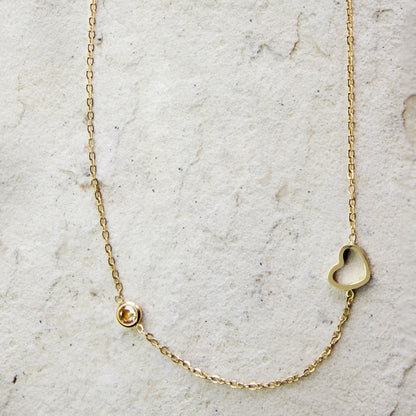 Elegant gold-plated necklace from Dahlia Jewels, featuring a delicate chain with a small, heart-shaped charm and a single zircon gemstone for a subtle touch of sparkle. This minimalist design is perfect for everyday wear or as a thoughtful gift, blending simplicity with a hint of luxury. Secures with a classic lobster clasp, ensuring a comfortable and adjustable fit. Available for free delivery in Nairobi. Keywords: jewellery, jewelry.
