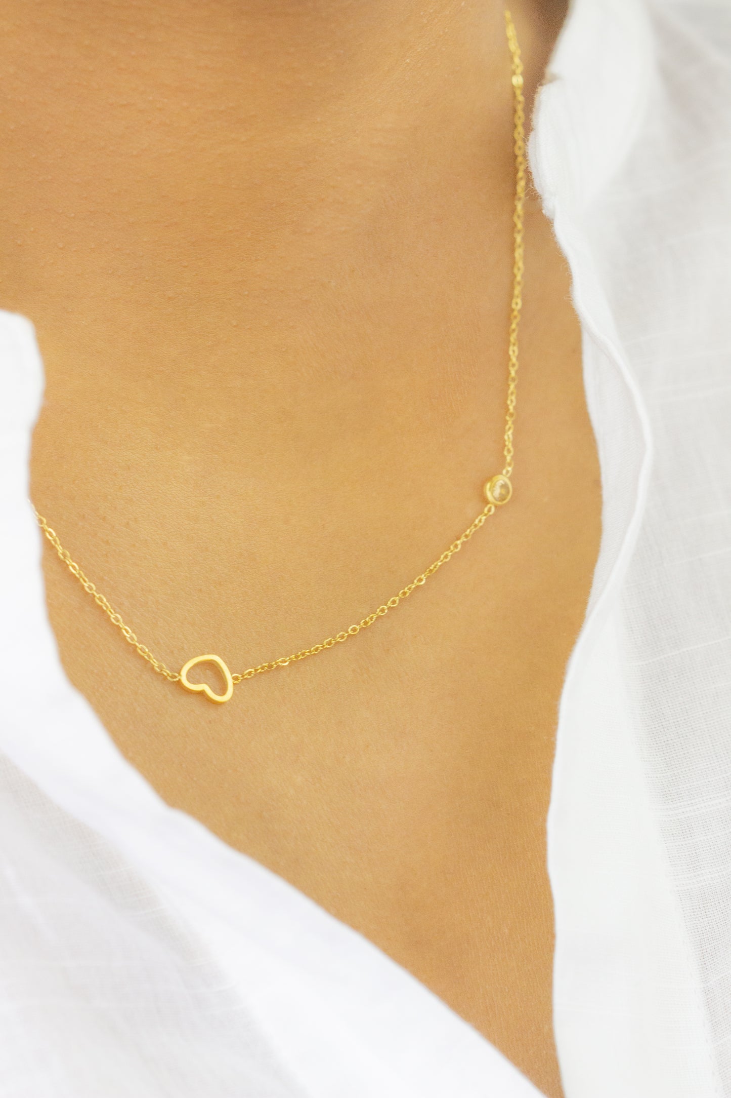 A model showcasing a delicate gold necklace with a heart pendant from Dahlia Jewels. The simple and elegant design of the necklace complements the model's attire. Dahlia Jewels offers free delivery in Nairobi.