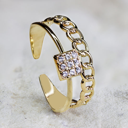 Stylish gold-plated ring from Dahlia Jewels featuring a unique split band design. One side of the band is adorned with a chunky chain link, while the other side is smooth and sleek. The centerpiece is a square setting encrusted with sparkling rhinestones, adding a luxurious touch to this contemporary piece. Perfect for adding a sophisticated flair to any ensemble. Enjoy free delivery in Nairobi. Keywords: jewellery, jewelry.