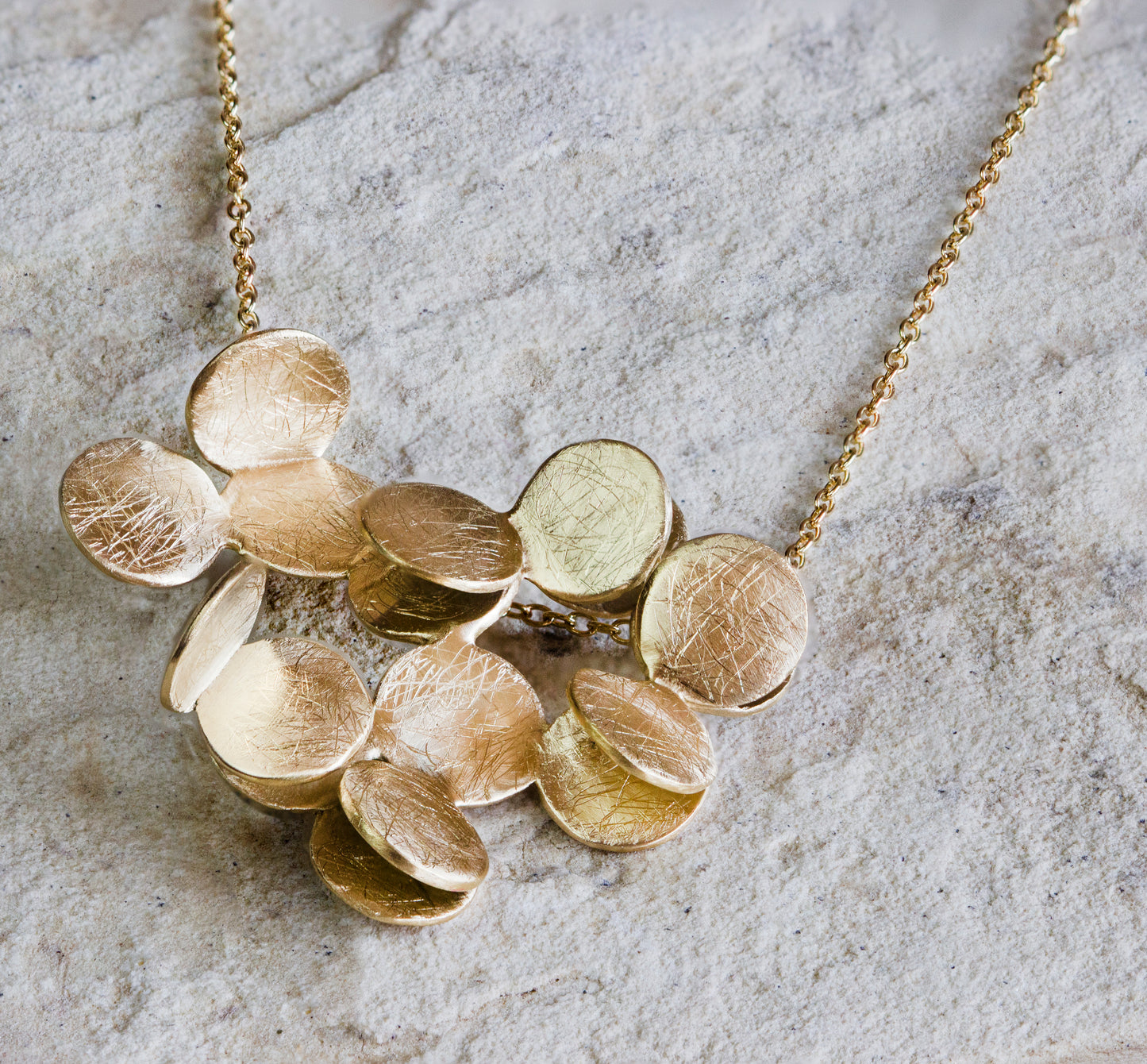 Beautiful gold necklace featuring a cluster of textured, overlapping discs with a scratched, matte finish. This statement piece adds a touch of modern elegance and charm to any outfit. Available with free delivery in Nairobi. #gorgeouseveryday