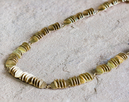 Elegant gold necklace featuring multiple clusters of textured, overlapping discs with a matte finish. This distinctive design creates a sophisticated, layered look, perfect for making a statement. Available with free delivery in Nairobi. #gorgeouseveryday