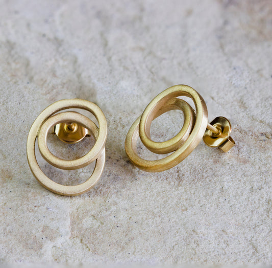 Modern gold stud earrings featuring an intertwined, circular design with a smooth, matte finish. These unique earrings offer a stylish and contemporary look, perfect for everyday wear or special occasions. Available with free delivery in Nairobi. #gorgeouseveryday