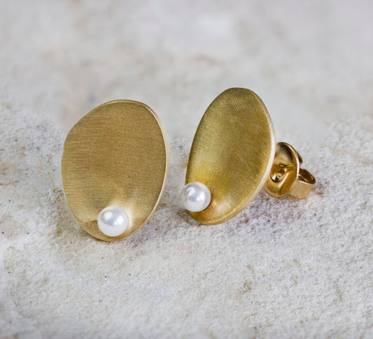 Elegant gold stud earrings featuring a unique oval shape with a lustrous pearl accent. The smooth, matte finish complements the timeless design, making them perfect for any occasion. Available with free delivery in Nairobi. #gorgeouseveryday