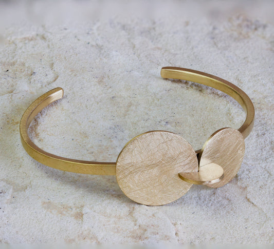 Modern gold cuff bracelet featuring a minimalist design with two textured, interlocking discs and a matte finish. This elegant piece adds a subtle yet sophisticated touch to any look. Available with free delivery in Nairobi. #gorgeouseveryday