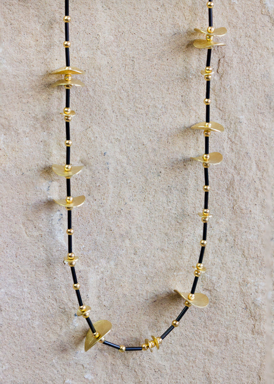 Unique gold necklace featuring a combination of gold beads and textured discs strung on a sleek black cord. This modern and artistic design adds a bold, contemporary touch to any outfit. Available with free delivery in Nairobi. #gorgeouseveryday