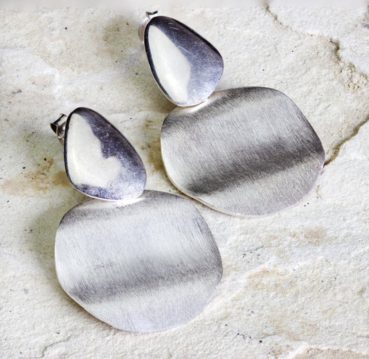 Large satin-finished silver teardrop stud earrings connected to brushed silver geometric plates, offering a modern and minimalist style, with Nairobi delivery #gorgeouseveryday