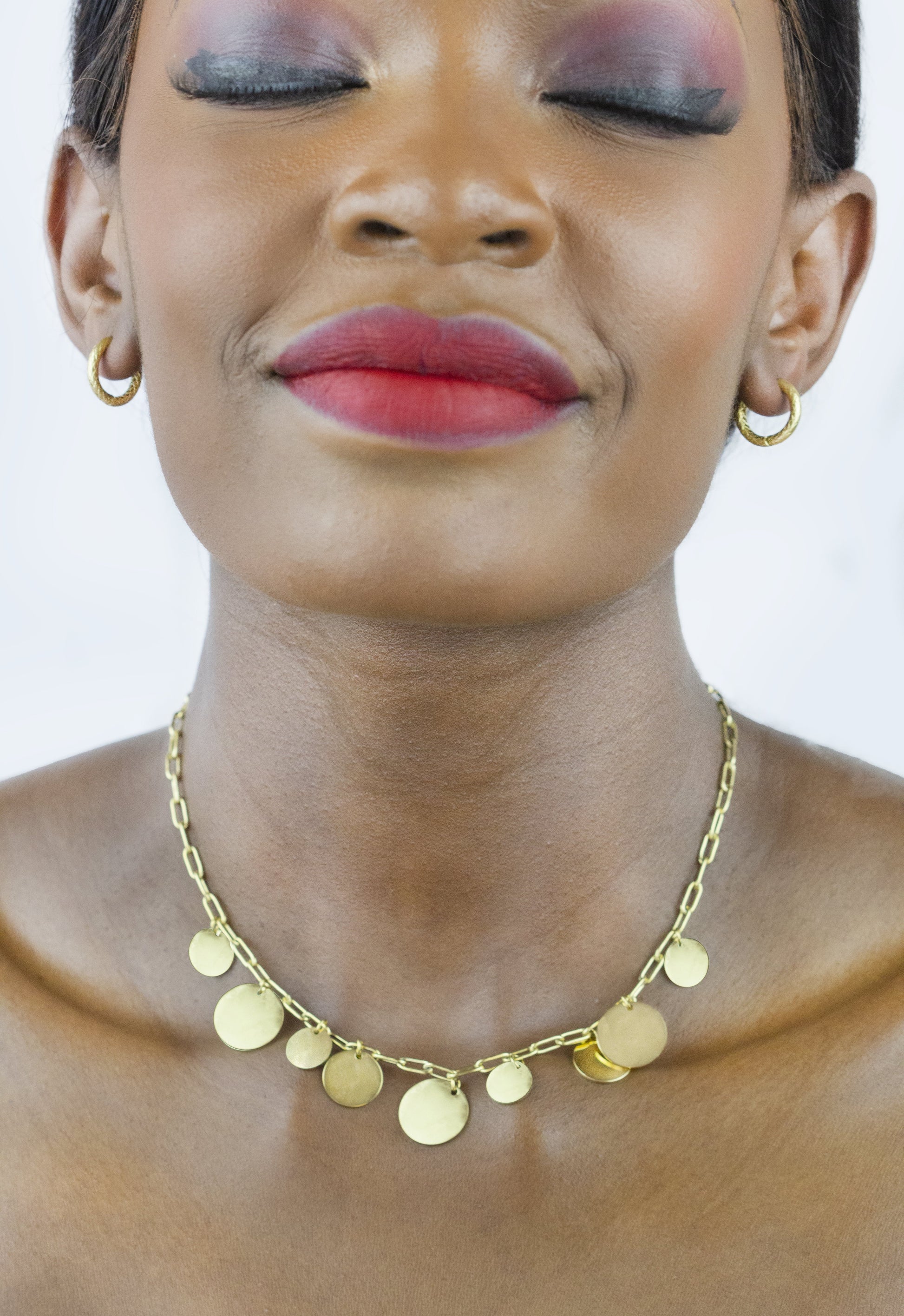 Dahlia Jewels' model wears a gold-plated disc necklace, ideal for making a statement anywhere and anytime. Free jewelry delivery in Nairobi.