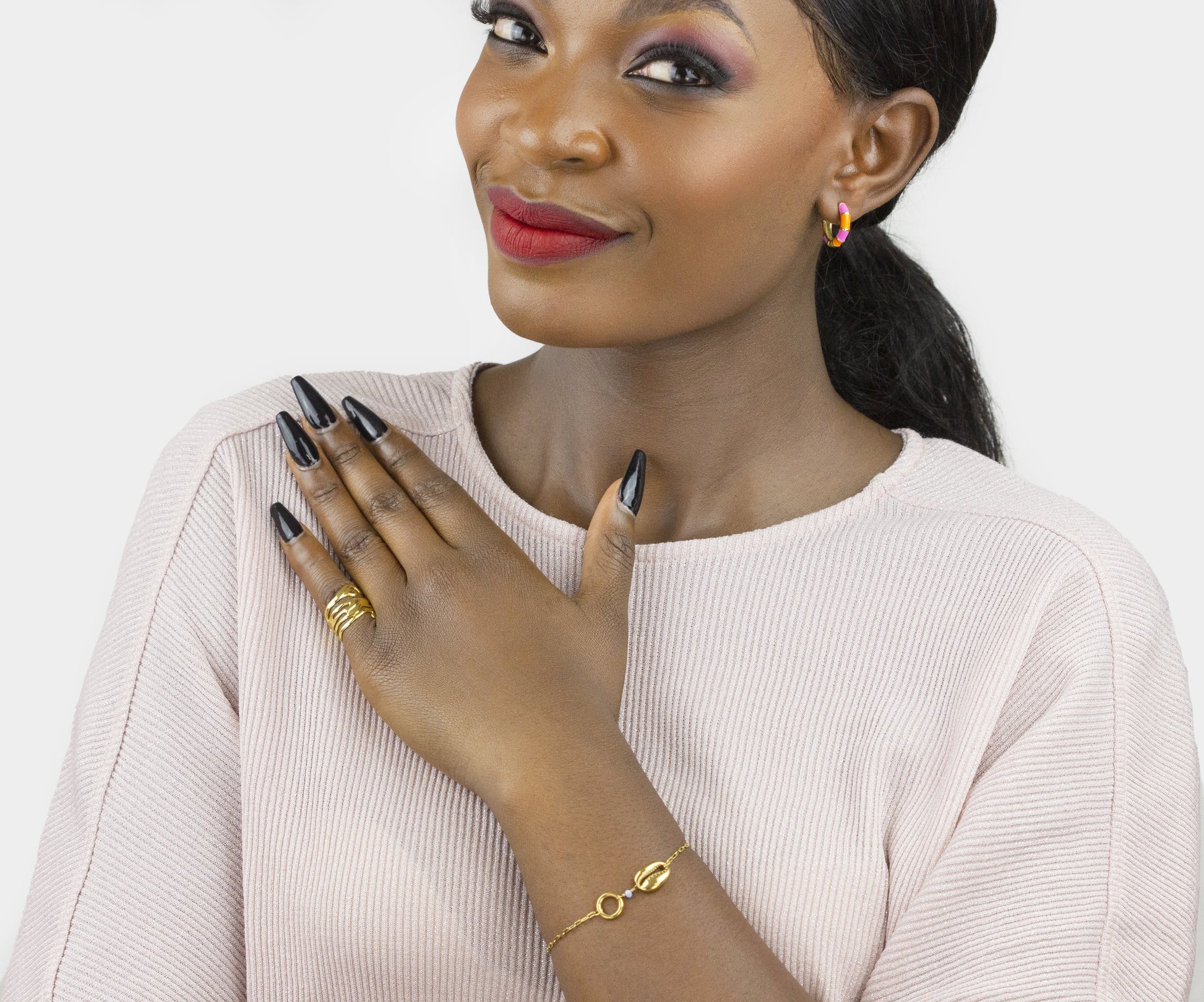A model elegantly showcases a Dahlia Jewels bracelet and ring, complemented by her black manicure and soft pink sweater. Free delivery in Nairobi.