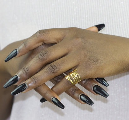 A model presents a Dahlia Jewels ring featuring an abstract golden design that makes a bold statement against her stylish black manicure. This piece highlights the brand's unique jewellery/jewelry offerings, all with the perk of free delivery within Nairobi.