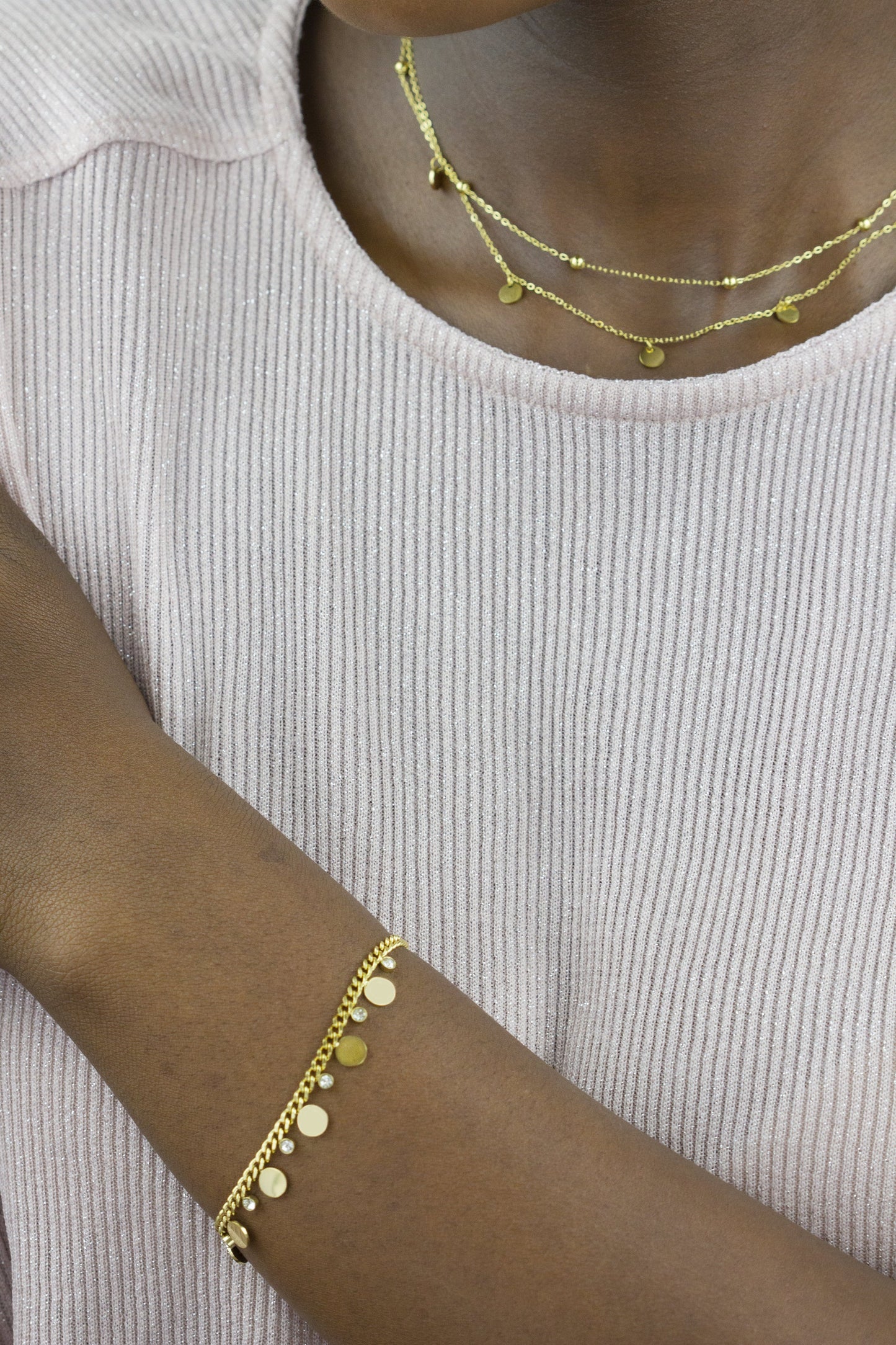 A model showcases a gold-tone bracelet and necklace from Dahlia Jewels. The bracelet is adorned with small discs and gems, while the necklace features a double-chain design with discs, adding an elegant touch. Free delivery in Nairobi.