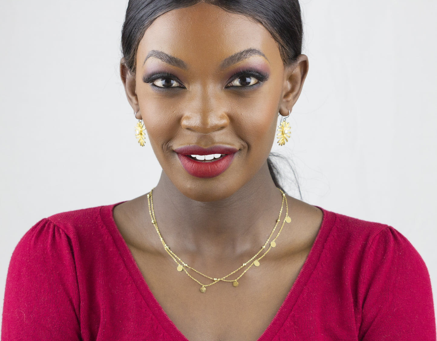 Model in a graceful pose, highlighting Dahlia Jewels' earrings and a necklace, perfect for any style. Free Nairobi delivery for your jewellery needs.